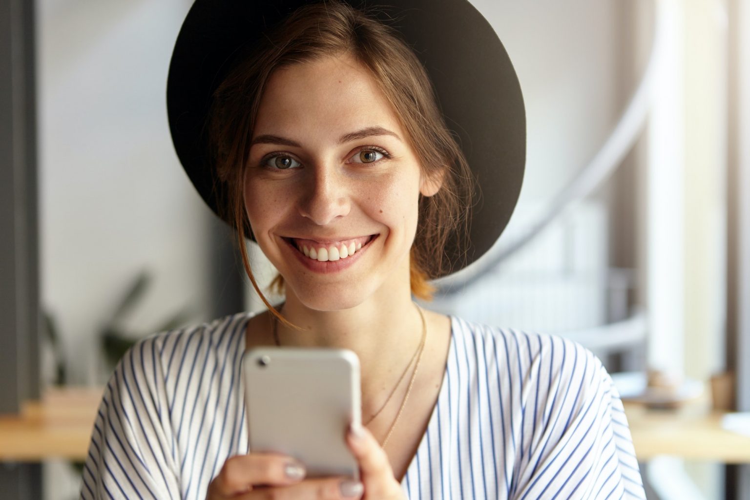 Headshot of fashionable cute young European female chatting online using wireless internet connectio